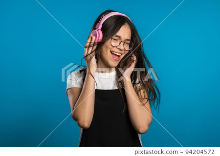 Pretty young asian girl with long hair having fun, smiling, dancing with headphones in studio Pretty young asian girl with long hair having fun, smiling, dancing with headphones in studio 94204572