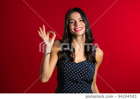 Young woman with perfect make-up making OK sign over red background. Winner. Success. Positive girl Young woman with perfect make-up making OK sign over red background. Winner. Success. Positive girl 94204583