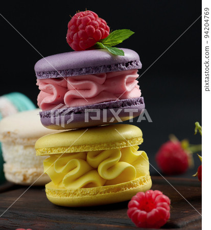 A stack of multi-colored macaroons on a wooden board. Delicious dessert 94204769
