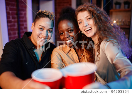 Cheerful pretty girls clinking with plastic glasses and looking at camera 94205564