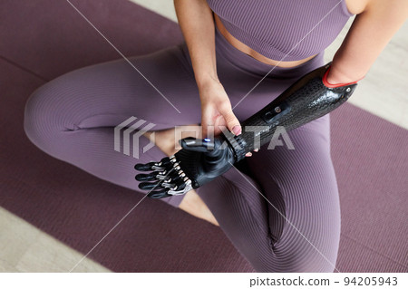 Woman with prosthetic arm exercising 94205943