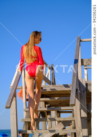 Stylish female on wooden structure on beach 94206261
