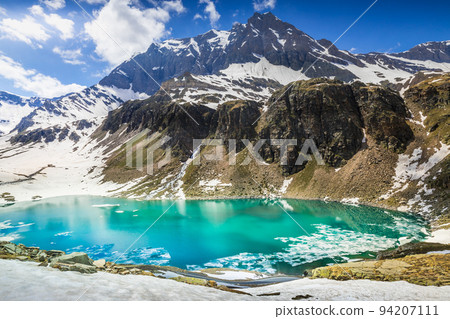 Alpine emerald lake and mountains at springtime, Gran Paradiso Alps, Italy 94207111