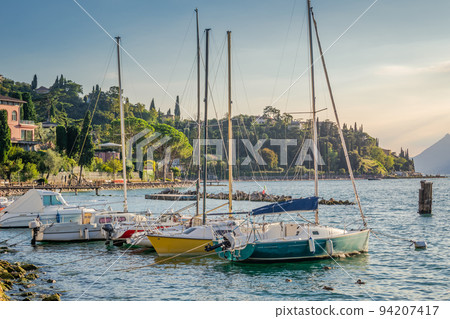 Idyllic lake Garda coastline and mediterranean village with sailboats, Italy Idyllic lake Garda coastline and mediterranean village with sailboats, Italy 94207417