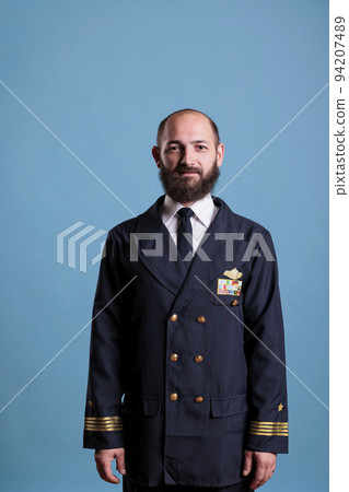 Smiling airplane captain wearing uniform medium close up portrait, plane aviator looking at camera. Middle age pilot with civil badge on professional suit, aircrew member Smiling airplane captain wearing uniform medium close up portrait, plane aviator looking at camera. Middle age pilot with civil badge on professional suit, aircrew member 94207489