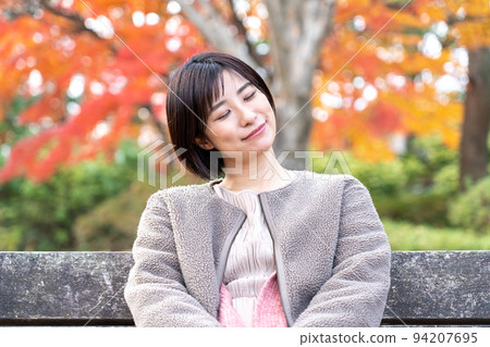 A young woman taking a nap in a park of autumn leaves A young woman taking a nap in a park of autumn leaves 94207695