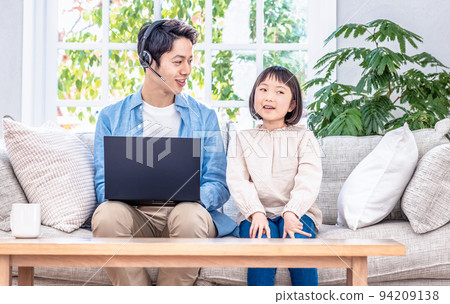 一個孩子坐在沙發上和一個在筆記本電腦上工作的爸爸交談 一個孩子坐在沙發上和一個在筆記本電腦上工作的爸爸交談 94209138