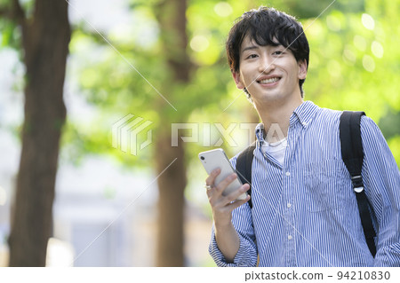 A smiling young man with a smartphone A smiling young man with a smartphone 94210830