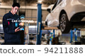 Asian man fix Technology AI fix car repair on car Lift in garage dealership Fix the car with a touch touching UI screen interface point to the point  corrected New technology in IOT car industry 94211888