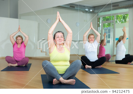 Group of active mature women practicing yoga Group of active mature women practicing yoga 94212475