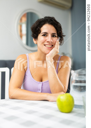 Portrait of woman sitting at a table in her apartment room 94212608