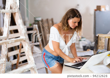 Seductive woman using laptop in apartment, home improvement works 94212628