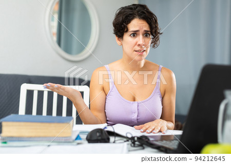 Dissatisfied woman chatting with someone over internet using laptop 94212645