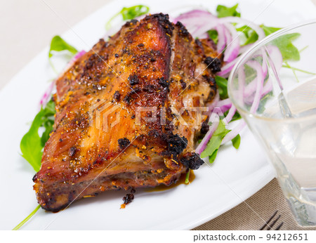 Tasty pork ribs baked under sauce, served with arugula and onion salad Tasty pork ribs baked under sauce, served with arugula and onion salad 94212651