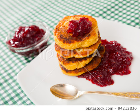 Stack of tasty fried quark pancakes served with berry jam 94212830