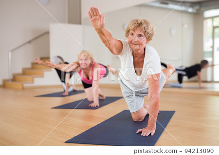 Senior woman practicing Balancing Table pose during group yoga training 94213090