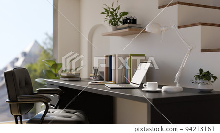 Minimal home office working space interior design with laptop on modern black desk against the stairs 94213161