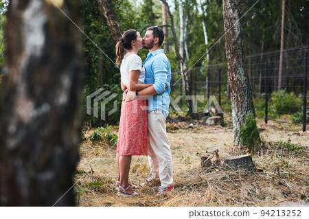Portrait of a young couple kissing on a date in the woods. Front view. Portrait of a young couple kissing on a date in the woods. Front view. 94213252