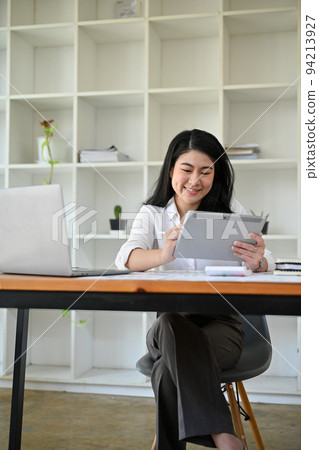 Portrait, Asian businesswoman at her office desk using digital tablet. 94213927
