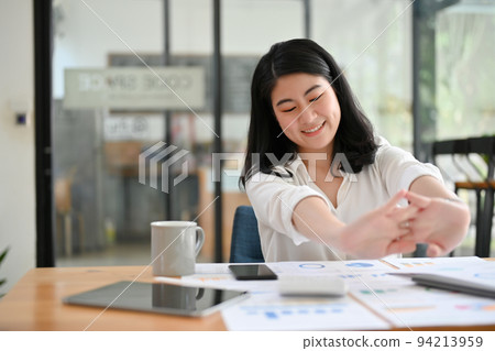 Beautiful young Asian businesswoman stretching her hands during working. 94213959