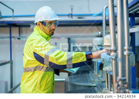 Senior professional quality control officer inspecting the manufacturing line and computer system in the beverage bottling factory. Industrial or machinery engineer inspecting and fixing the machines. 94214034