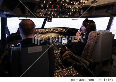 Male captain and copilot flying airplane with control command on dashboard navigation, looking through windscreen. Airliners team taking off with plane using power panel buttons. Male captain and copilot flying airplane with control command on dashboard navigation, looking through windscreen. Airliners team taking off with plane using power panel buttons. 94215165