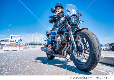 A female rider touring Yokohama on a large cruiser bike 94216198