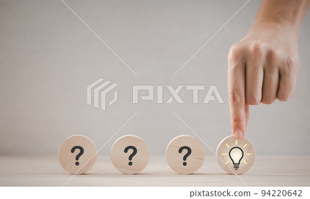 closeup hand holding round wood piece with light bulb icon 94220642