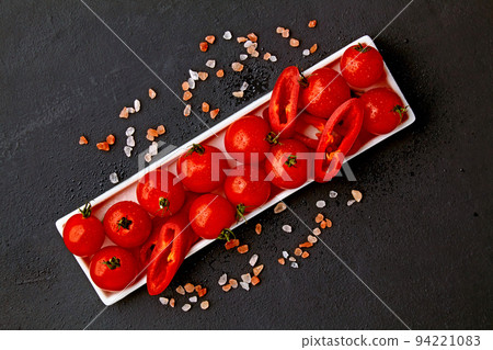 Fresh washed cherry tomatoes and paprika slices on a white oblong dish with pink salt and water drops on a black Fresh washed cherry tomatoes and paprika slices on a white oblong dish with pink salt and water drops on a black 94221083