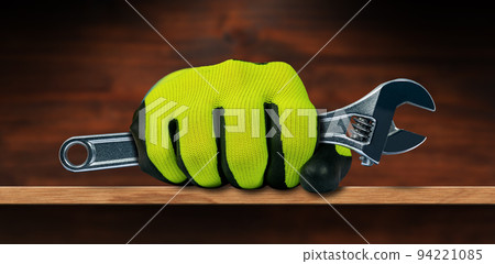 Hand with Protective Work Gloves Holding a Steel Adjustable Wrench Hand with Protective Work Gloves Holding a Steel Adjustable Wrench 94221085