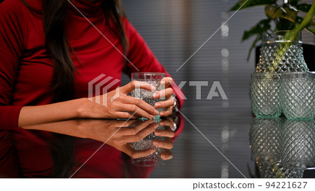 A beautiful Asian woman at the dining table holding a glass of water. A beautiful Asian woman at the dining table holding a glass of water. 94221627