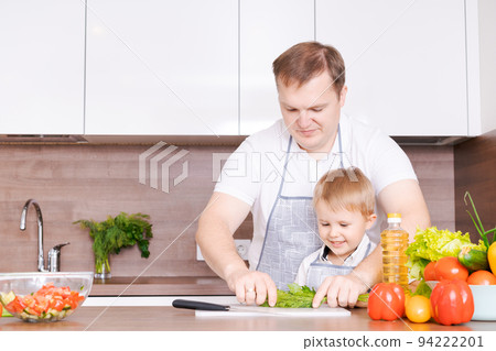 Loving father and little preschooler son cooking cut vegetables for salad 94222201