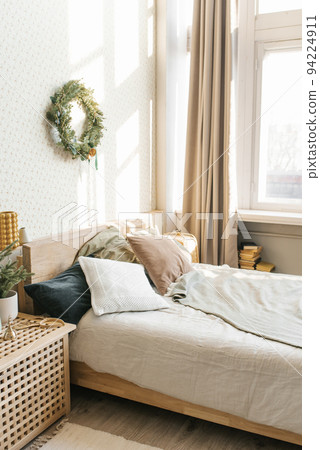 A bed with pillows and Christmas decorations in the bedroom in a Scandinavian style. Interior of the house 94224911