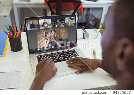 Over shoulder view of african american businessman making laptop video call with diverse colleagues 94225697