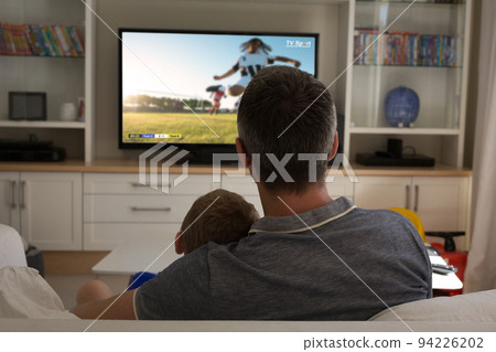 Father and son watching football match siting together on the couch Father and son watching football match siting together on the couch 94226202