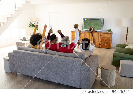 African american family watching football match siting together on the couch African american family watching football match siting together on the couch 94226205