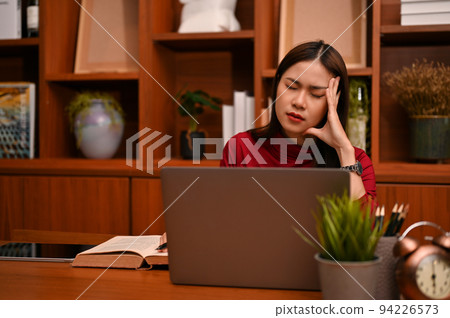 Stressed and frustrated Asian businesswoman suffering from headache Stressed and frustrated Asian businesswoman suffering from headache 94226573
