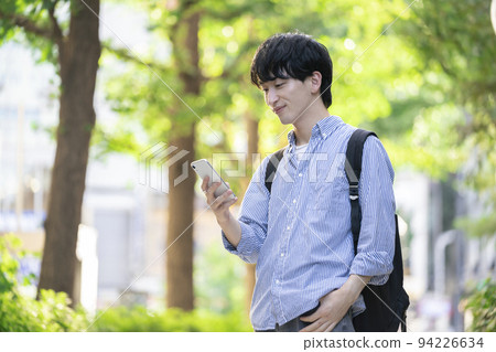 有智能手機的一個微笑的年輕人 有智能手機的一個微笑的年輕人 94226634