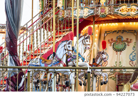 Horses on a carnival Merry Go Round. Old French carousel in a holiday park. Big roundabout at fair in amusement park Horses on a carnival Merry Go Round. Old French carousel in a holiday park. Big roundabout at fair in amusement park 94227073