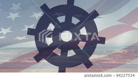 Image of turning ships wheel with american flag blowing over ocean and blue sky 94227534
