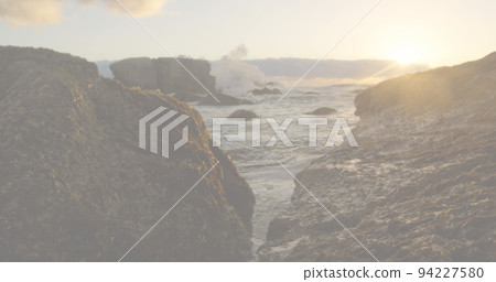 Image of red, white and blue squares and crossed american flags over rocks and ocean at sundown 94227580