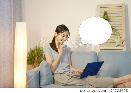 一位女士晚上在客廳裡使用筆記本電腦，並帶有語音氣泡 94228728