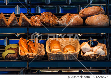 Freshly baked bread on a shelves in bakery, baguette and rolls. Different types of delicious loaves of bread in a german baker shop 94228876