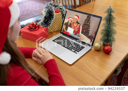 Caucasian woman in santa hat making laptop christmas video call with smiling mother and daughter Caucasian woman in santa hat making laptop christmas video call with smiling mother and daughter 94229337