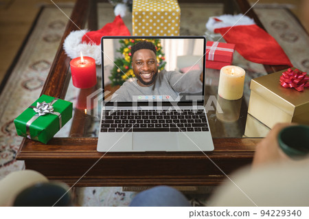 Smiling african american man at christmas smiling on laptop video call screen Smiling african american man at christmas smiling on laptop video call screen 94229340