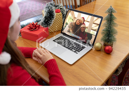 Caucasian woman in santa hat making laptop christmas video call with smiling mother and daughter Caucasian woman in santa hat making laptop christmas video call with smiling mother and daughter 94229435