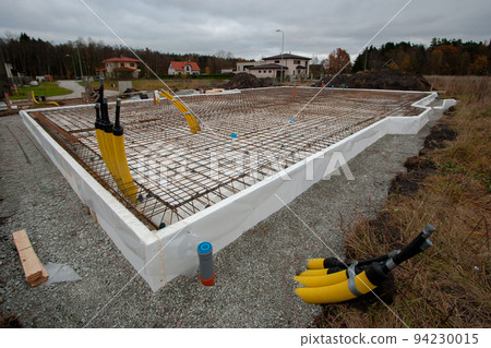 Reinforcement of foundation slab of private house. Preparation for pouring concrete foundation for house. Plinth is insulated with foam. Pavement is strewn with rubble. 94230015