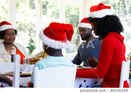 Multi generation african american family sitting at table and praying before dinner Multi generation african american family sitting at table and praying before dinner 94230104