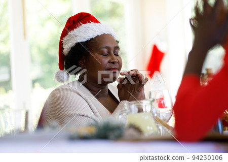 Senior african american woman sitting at table and praying before dinner Senior african american woman sitting at table and praying before dinner 94230106