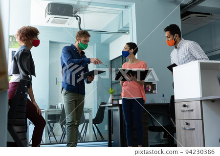 Diverse group of work colleagues wearing masks in discussion office Diverse group of work colleagues wearing masks in discussion office 94230386
